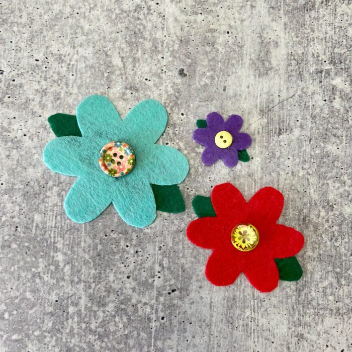 three felt flowers with buttons on a table