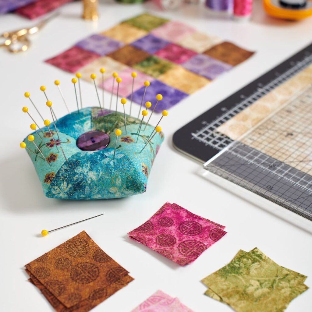 Pin cushion and quilt fabric on a table.